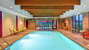 An indoor swimming pool with wooden ceiling beams, yellow chairs, and tables along the sides. - Home2 Suites by Hilton Rochester Mayo Clinic Area (Rochester)