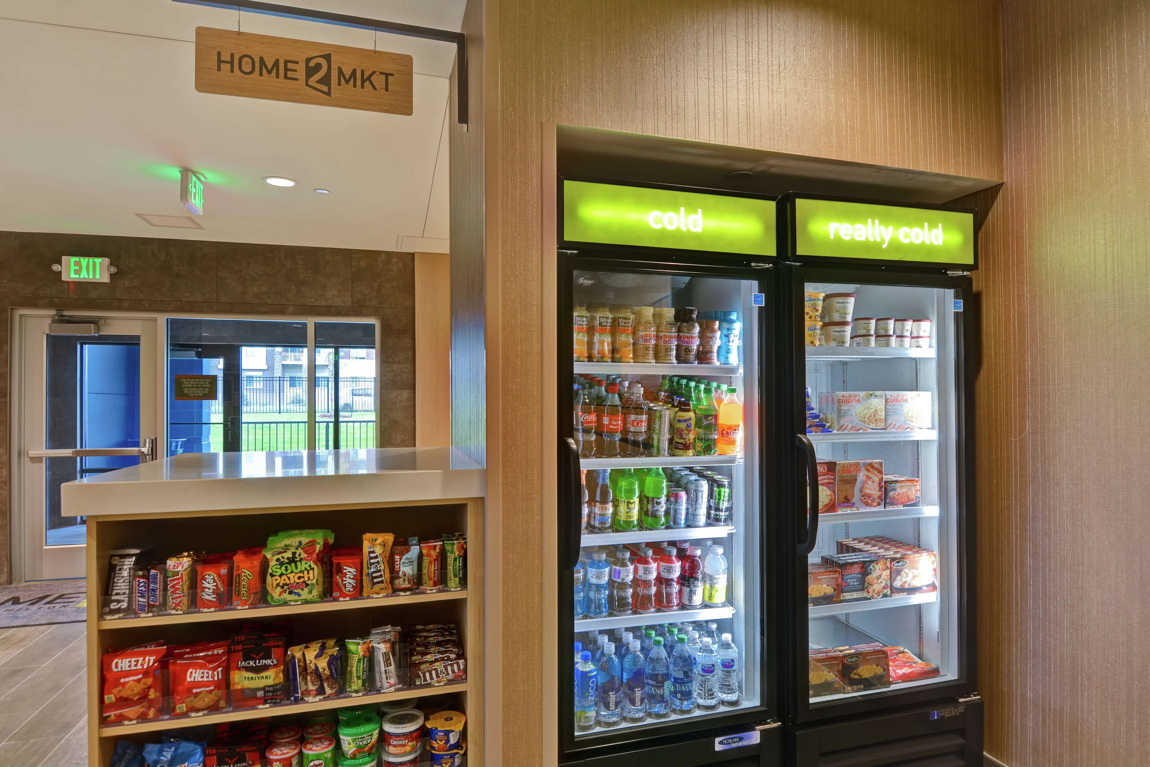Un área de venta automática con diferentes opciones de aperitivos y bebidas, incluyendo un refrigerador etiquetado como 'frío' y 'muy frío'.