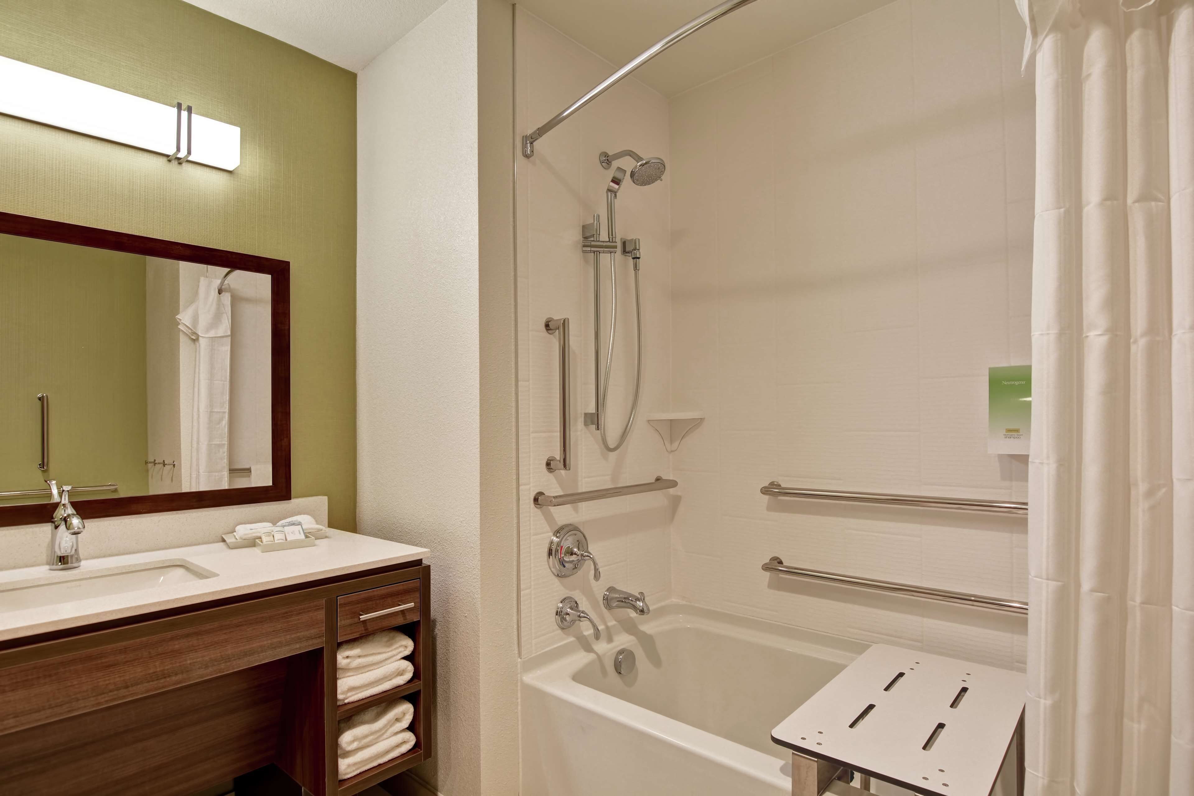 Un baño moderno con un lavamanos, espejo y bañera blancos.