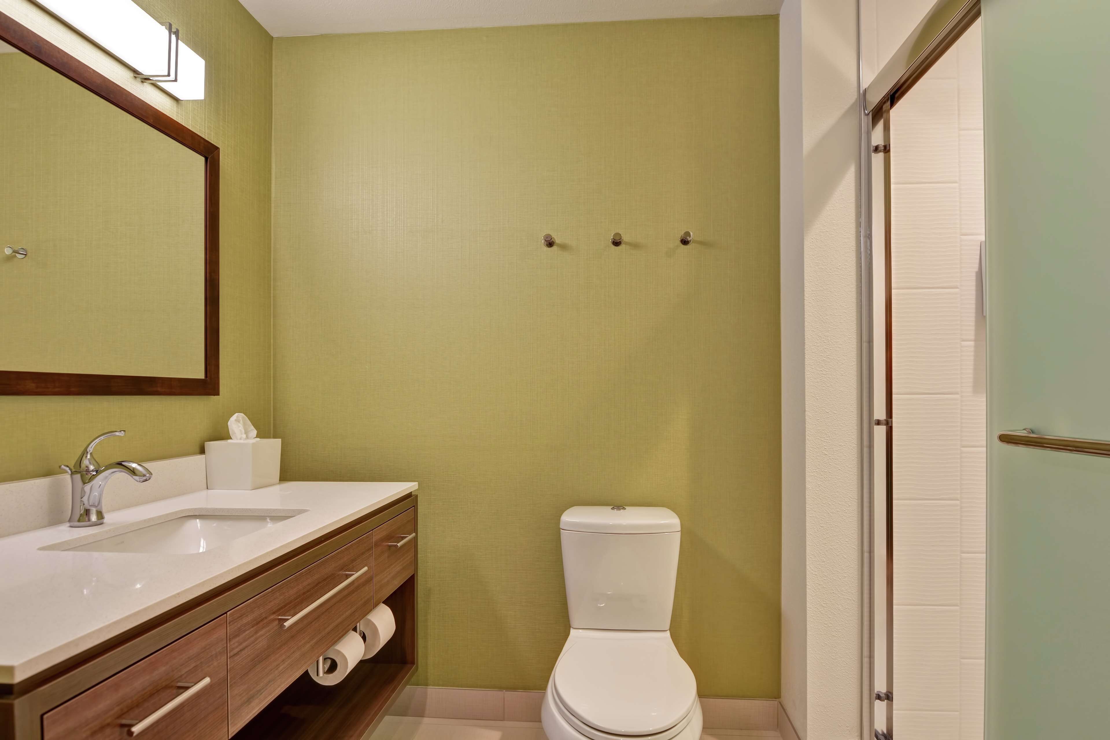 A bathroom with a sink, mirror, toilet, and towel rack.