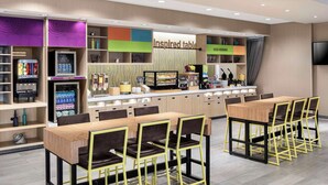 A modern restaurant with a counter, seating area, and a TV screen. - Home2 Suites by Hilton Rochester Mayo Clinic Area (Rochester)