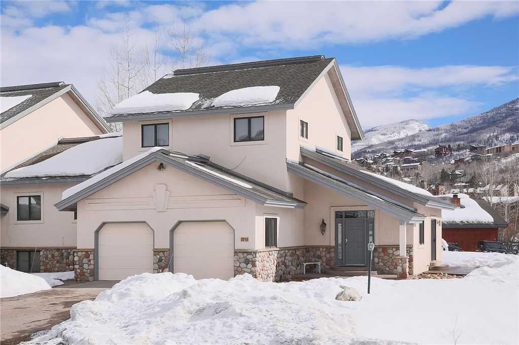 Une maison à deux étages avec des fondations en pierre, un garage et une all ée couverte.