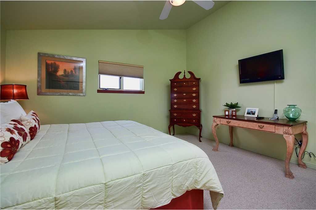 A bedroom with a bed, a dresser, a television, and a window.