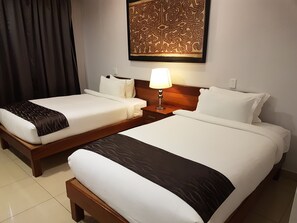 Une chambre d’hôtel avec deux lits simples, une table de chevet avec une lampe et un élément décoratif mural au-dessus des lits.