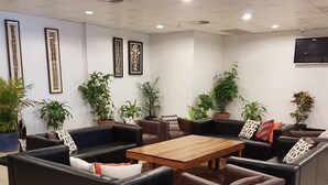Un espace détente moderne avec des canapés en cuir, une table basse en bois et des plantes en pot.