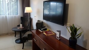 Une chambre d’hôtel équipée d’un bureau, d’une chaise, d’une télévision, d’une lampe et d’une plante en pot.