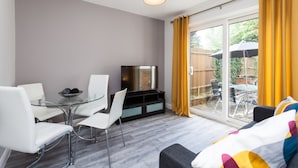 A modern living room with a glass table, white chairs, a sofa, and a TV. - The Northgate (Crawley)