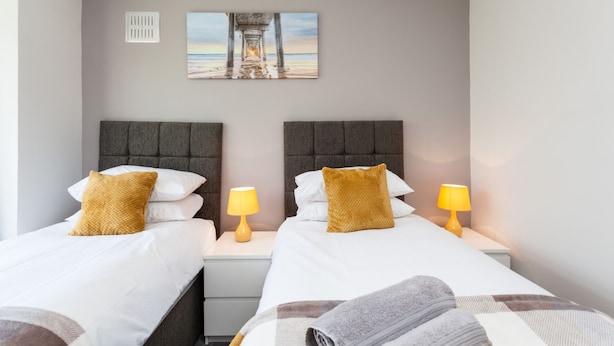 A hotel room with two beds, a painting of a pier, a white wall, and a window. - The Northgate (Crawley)