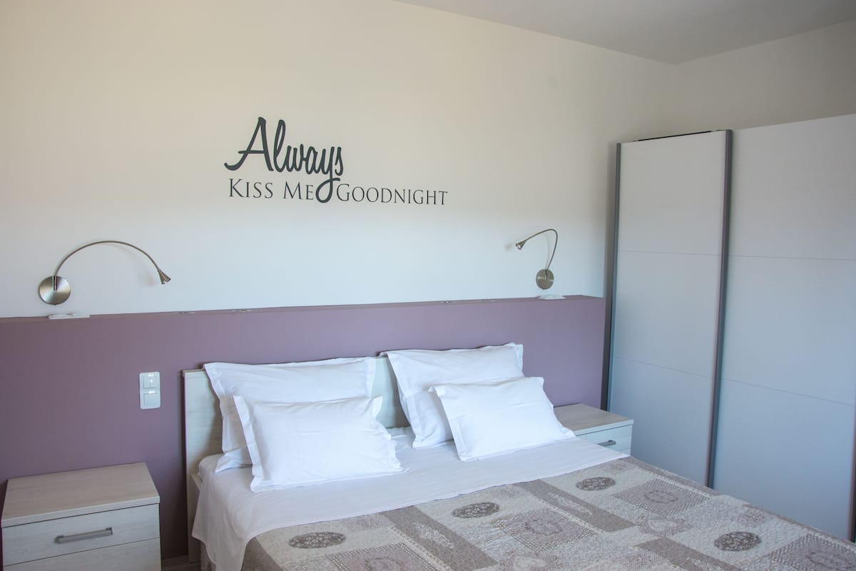 Un dormitorio con cama, mesita de noche, lámpara de pared y armario.