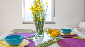 A dining table with a vase of yellow flowers, blue bowls, and a glass of water. - Apartments Villa Franci (Pag)