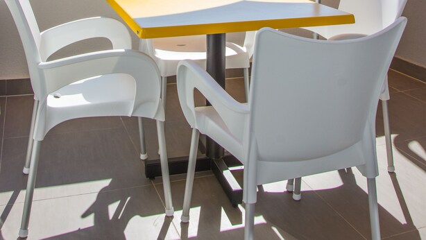 A terrace with a table and chairs, an umbrella, and a view of a town and hills in the background. - Apartments Villa Franci (Pag)