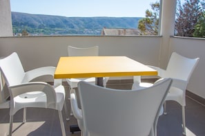 A balcony with a table and chairs, offering a view of a mountainous landscape.