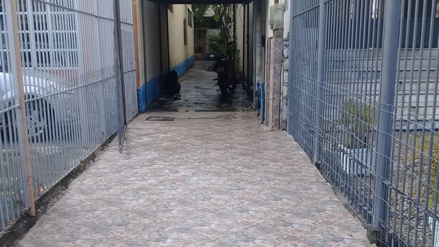 Ein Hostel Eingang mit einem gefliesten Weg, der zu einem umzäunten Bereich führt.