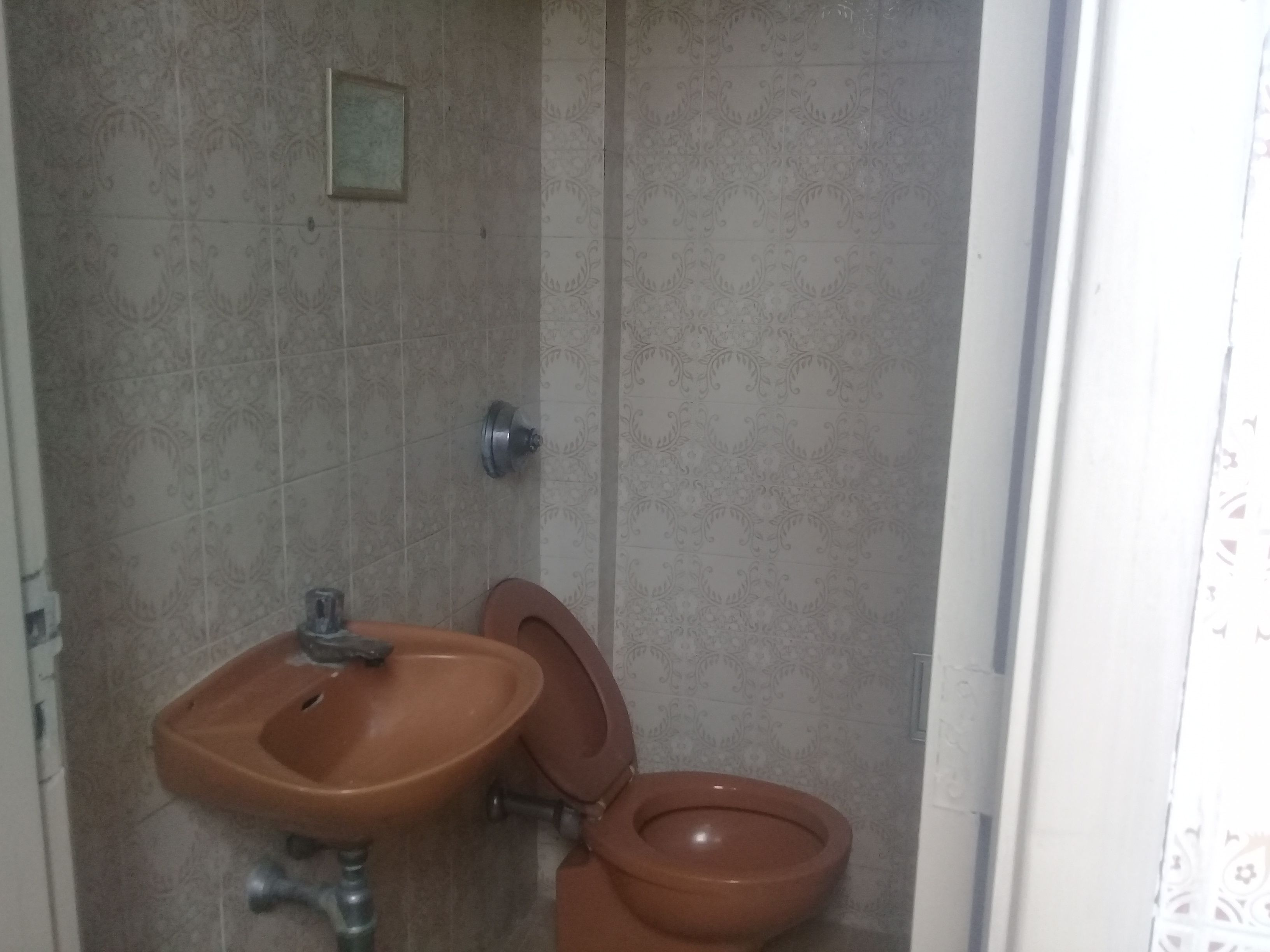 Une salle de bain avec un lavabo et des toilettes, des murs carrelés et un espace douche.
