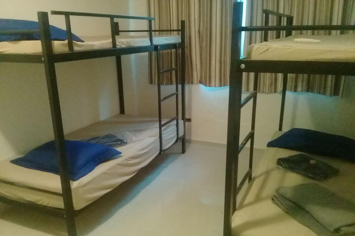 A bunk bed room with two beds, a curtain, and a window.