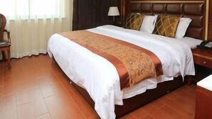 Una habitación de hotel con una cama grande, una mesita de noche, una silla y una ventana con cortinas.