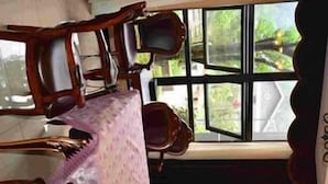 Una habitación con un ventanal grande, una mesa de comedor con sillas y vistas a zonas verdes.