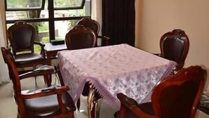 Un comedor con una mesa cubierta por un mantel estampado, rodeado de sillas de madera.