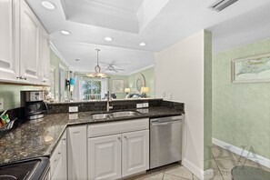 A modern kitchen with white cabinets, granite countertops, a stainless steel sink, and a dishwasher.