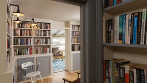 A cozy reading nook with bookshelves filled with books, a comfortable chair, and a small table. - The Deers Head Inn (Elizabethtown)