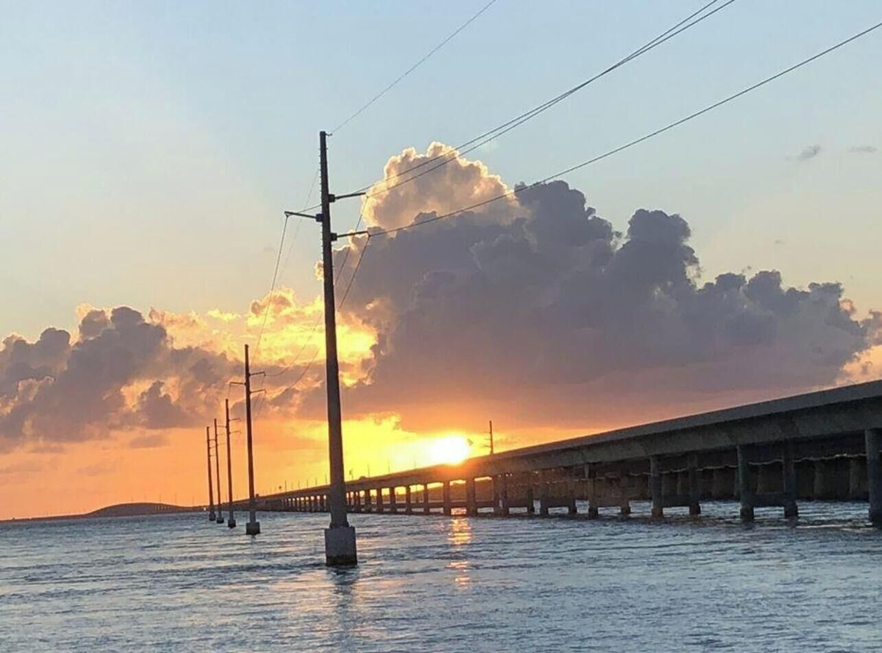 A bridge over water during sunset with a clear sky.
