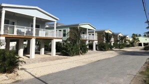 A row of beachfront houses with balconies, a sandy driveway, and palm trees. - 🌸Home(#5) “AFTER DUNE🍹DELIGHT”(-approximately 50 ft from Private beach entrance)🌸 (Marathon)