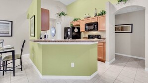 A modern kitchen with a central island, wooden cabinets, and a microwave. - VP2522DC - Pool Home - Conservation Views - Sleeps Up to 8 (Kissimmee)