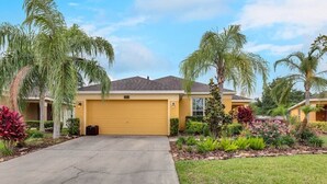 A residential house with a yellow garage door, surrounded by palm trees and well-maintained landscaping. - VP2522DC - Pool Home - Conservation Views - Sleeps Up to 8 (Kissimmee)