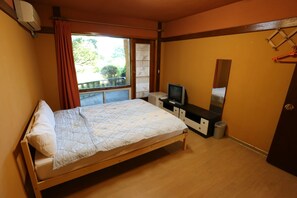 A bedroom with a bed, a TV, a dresser, and a window with curtains.