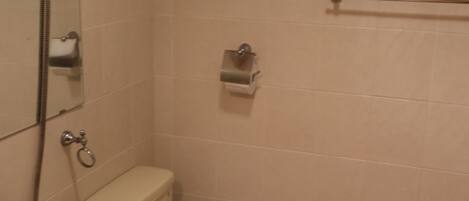 A small bathroom with a toilet, sink, and shower.