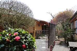A courtyard with a wooden bridge, a fenced area, and a building with a curved roof.