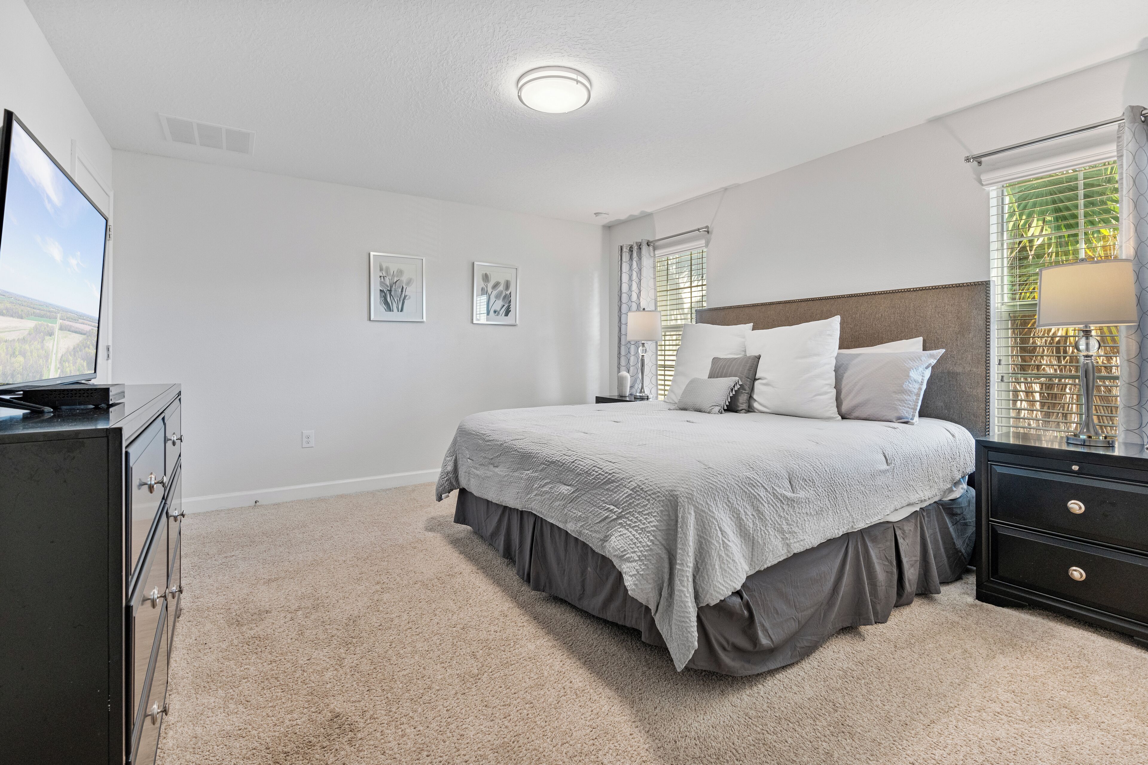 A bedroom with a bed, a dresser, and a television.