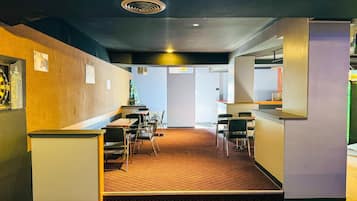 A modern interior with a patterned carpet, tables, chairs, and a vending machine.