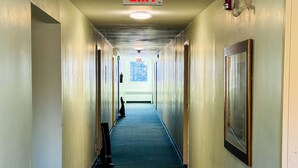 A hallway with an EXIT sign, a framed picture on the wall, and a signboard on the floor.