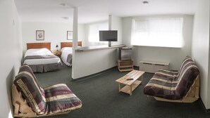 A compact hotel room with two beds, a small desk with a TV, a sofa, and a chair. - Asessippi Inn (Russell)