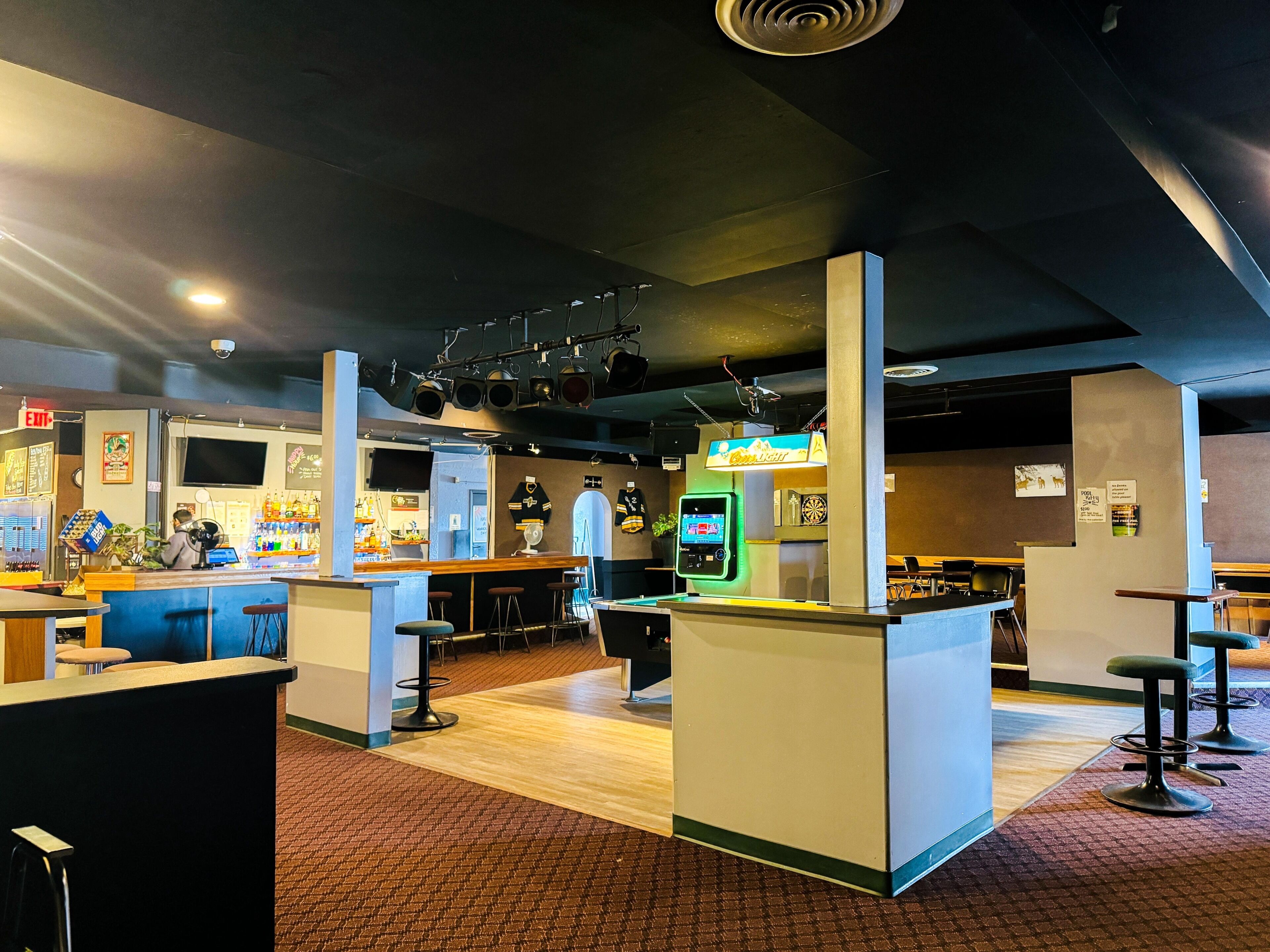Een bar met krukken, een toonbank en een neonbord.