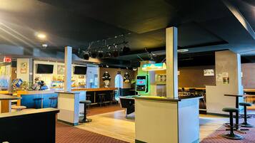Een bar met krukken, een toonbank en een neonbord.