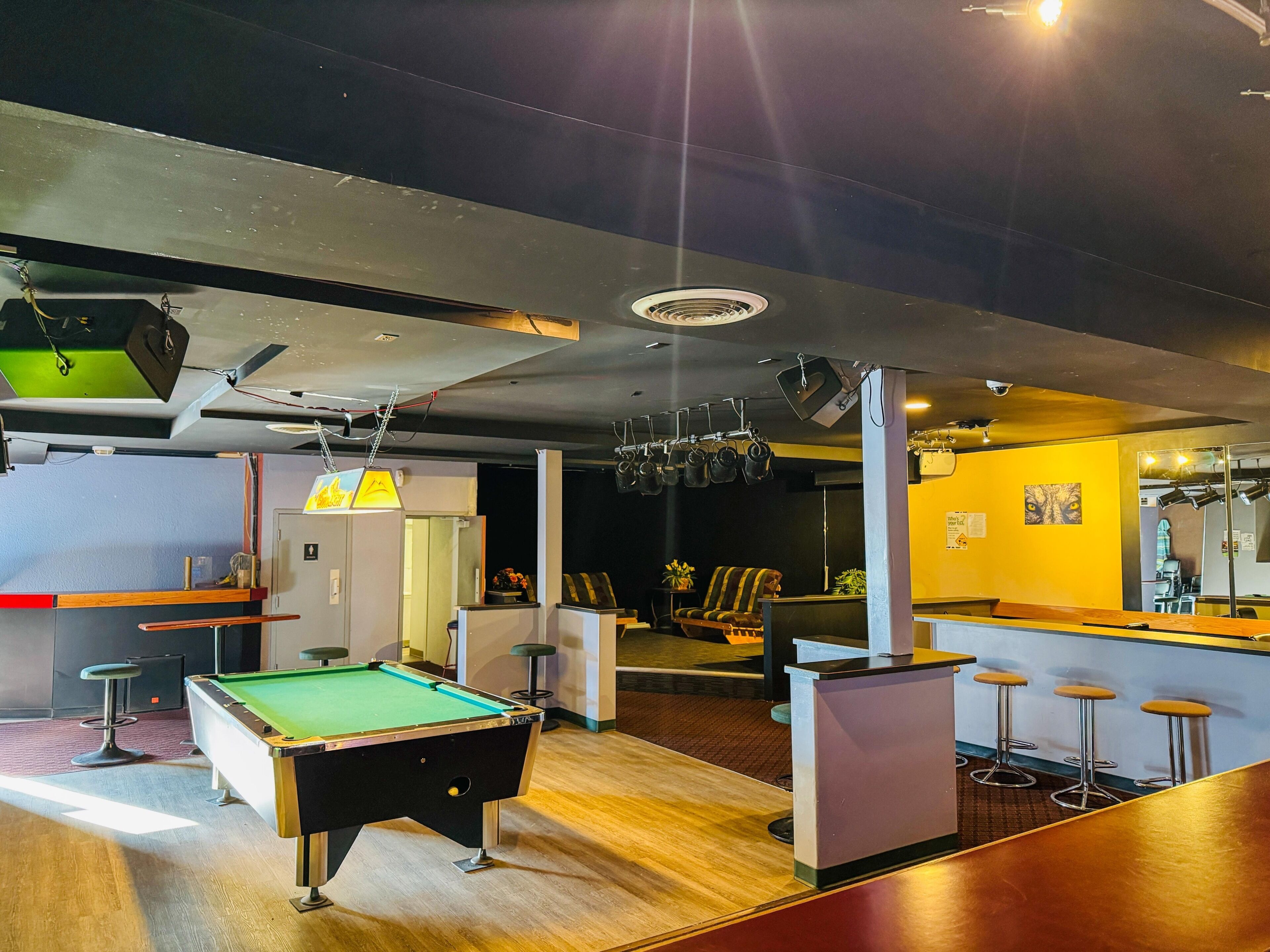 A billiards table, a bar area with stools, and a seating area with chairs.
