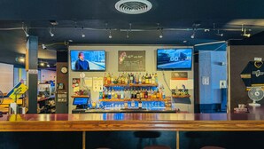 A bar area with a counter, stools, and multiple screens displaying content.