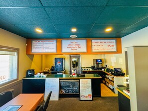 A cafe interior with a menu board, a coffee machine, and a seating area.