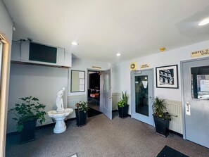 A hotel lobby with a statue, potted plants, a reception desk, and a check-in area.