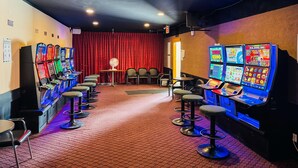 A room with slot machines, chairs, and a red curtain.