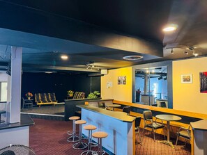 A bar area with stools, a counter, and a seating area with tables and chairs. - Asessippi Inn (Russell)