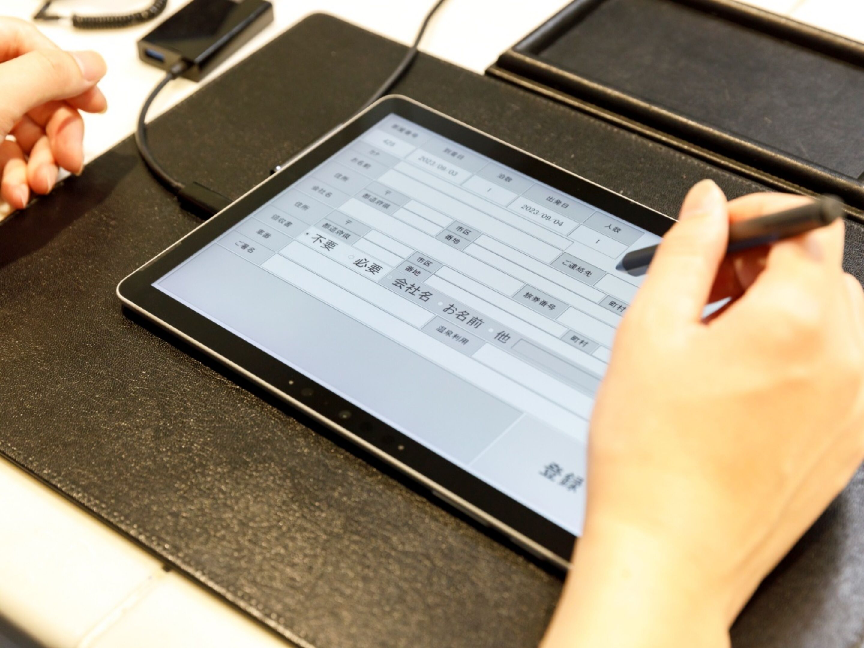A tablet on a stand with a person holding a stylus, displaying a table with text.