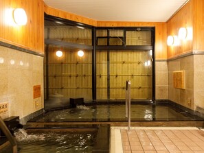A traditional Japanese onsen with a wooden interior, a hot spring bath, and tiled walls. - Miyazaki Lions Hotel (Miyazaki)