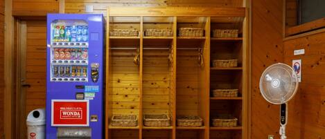 A room with a vending machine, wooden shelves, and a fan.