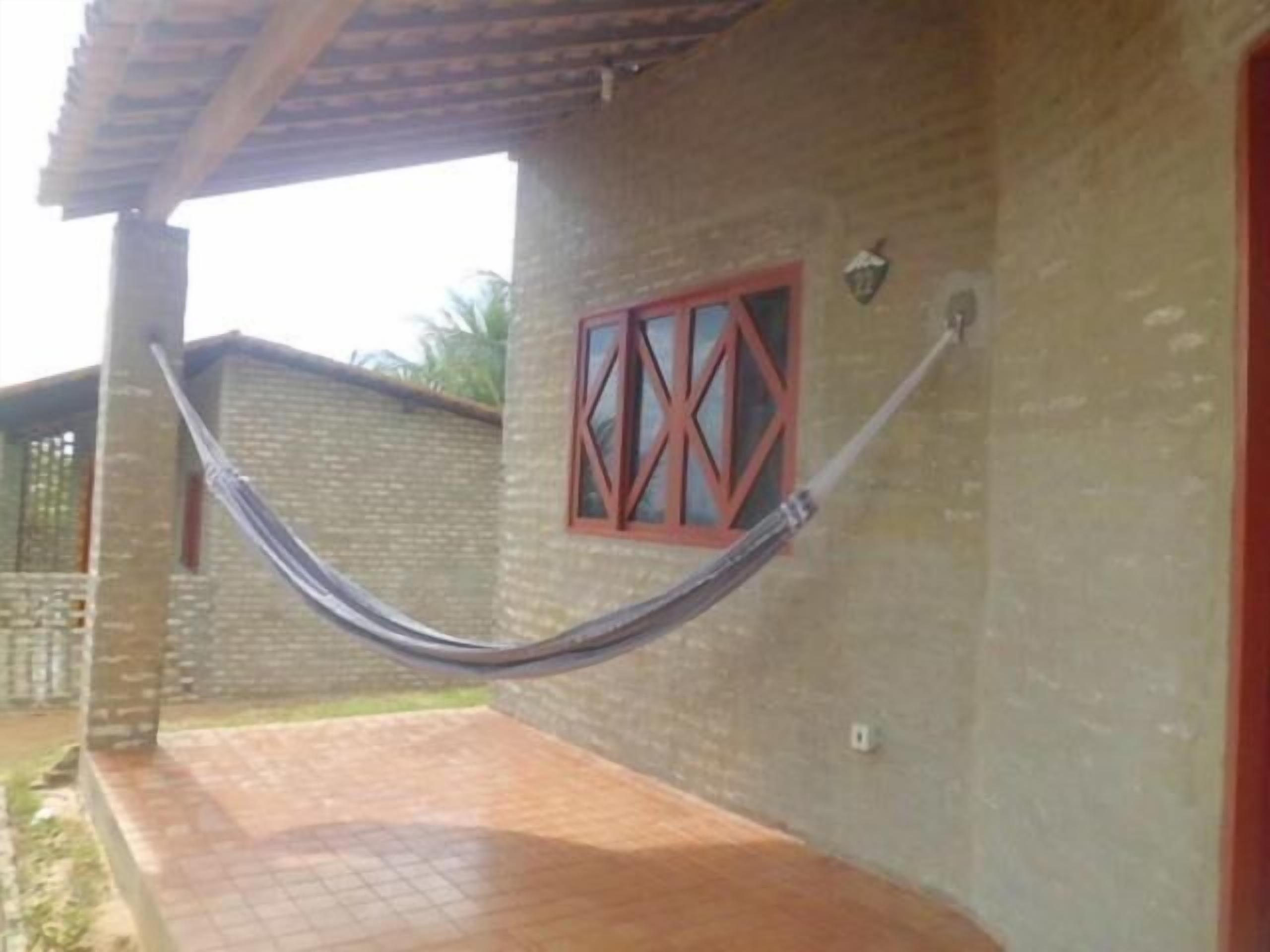 Una hamaca colgada entre dos muros de ladrillo con un ventanal.