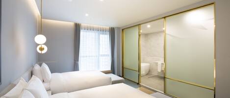 Ein modernes Hotelzimmer mit zwei Betten, einem großen Spiegel und einem durch eine Glaswand sichtbaren Badezimmer.