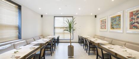 A conference room with long tables, chairs, and a central potted plant.