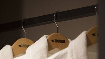 Un perchero con toallas blancas colgadas en perchas de madera con la etiqueta 'HOUND'.